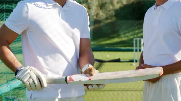 Cricket players interacting with each other during a practice session in the nets alt
