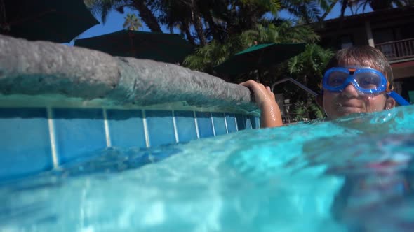 Underwater shot of a boy playing in a pool at a hotel resort. alt