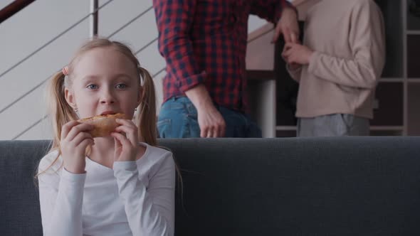 Little Girl Eating Pizza and Enjoying Tv Program While Her Paren