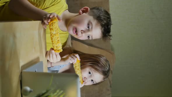 Brother and Sister Teenagers Watch Movies in Laptop and Eat Boiled Corn alt