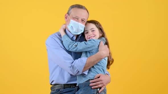 Granddaughter puts a mask on her face and gently hugs alt