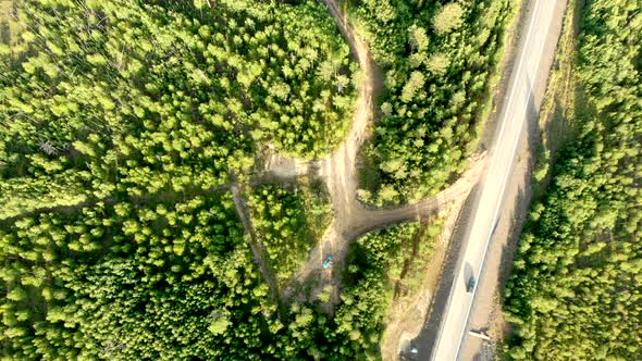 Aerial Stable Shot Over a Country Road with Few Cars Driving Between Forests