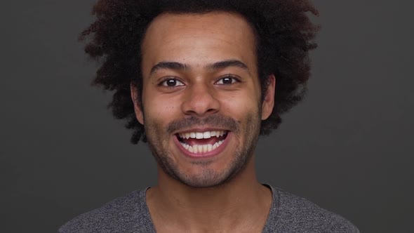 Dark Skinned Young Man with Afro Haircut Having Fun Showing His White Teeth Ang Tongue Over Charcoal alt