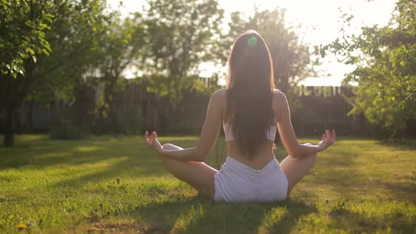 Young Woman Meditating and Relaxing Outdoors on the Grass