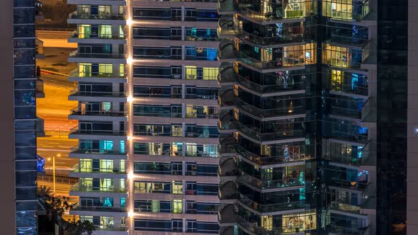 Glowing Windows in Multistory Modern Glass and Metal Residential Building Light Up at Night alt