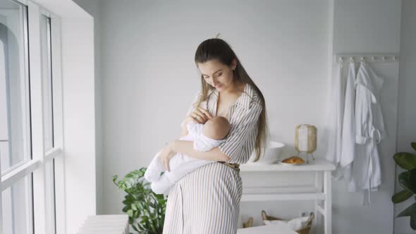 Young Mother Breastfeeds Baby at Home