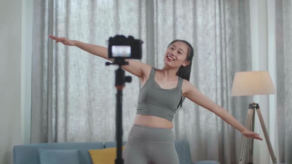 Asian Trainer Female In Sports Clothes Speaking To Camera And Stretching While Recording alt