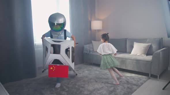 Chinese Kids Play in the Living Room of the House a Boy in an Astronaut Costume Plays with a alt