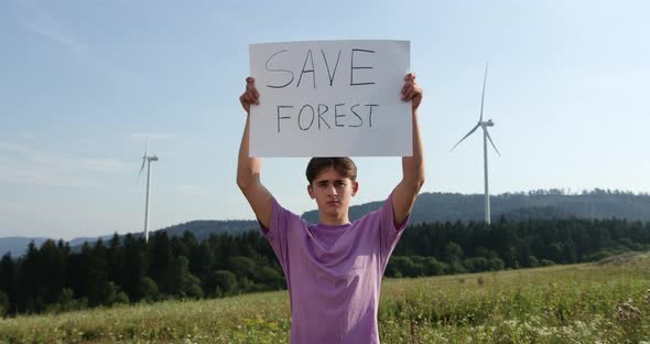Outdoor of Men Activist with Save Forest Ecology Poster. In Background Forest and Wind Turbine alt