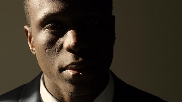 Depressed and sad young black business man in shadow alt