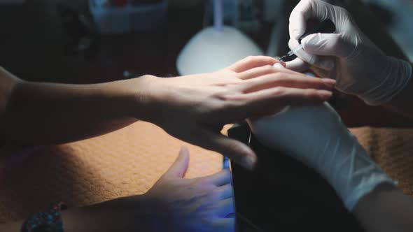 Applying Clear Varnish to Woman Nail in Salon
