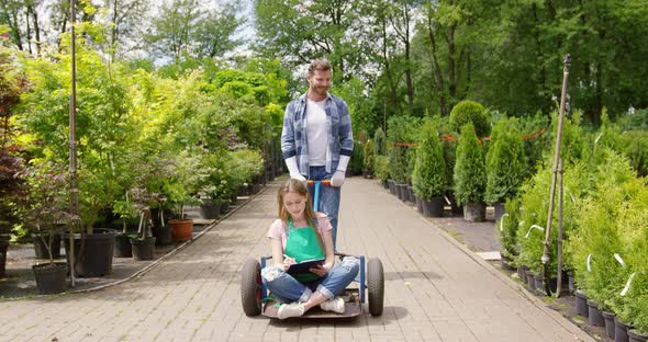 Woman Gardner Sitting on Wagon in Garden and Doing Paperwork alt