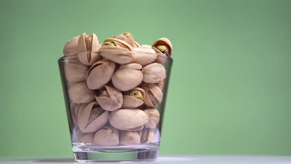 Roasted Pistachios in the Shell Are Rotated in the Сup on Pistachio Background