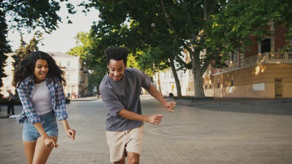 Darkskinned Couple Smiling and Dancing at City Square alt