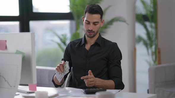 Young Rich Man Counting Cash Dollars Smiling Sitting in Home Office Indoors alt