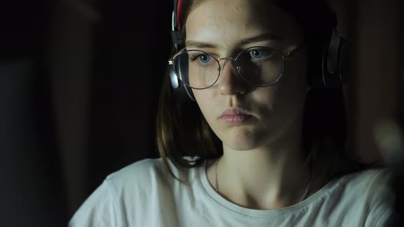 Teenage Girl with Glasses Looks at the Monitor Plays a Game Reads Studies Late at Night alt