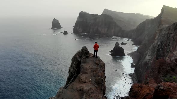 Drone Circle Around Man Hiker Standing on a Dangerous Cliff over the Ocean
