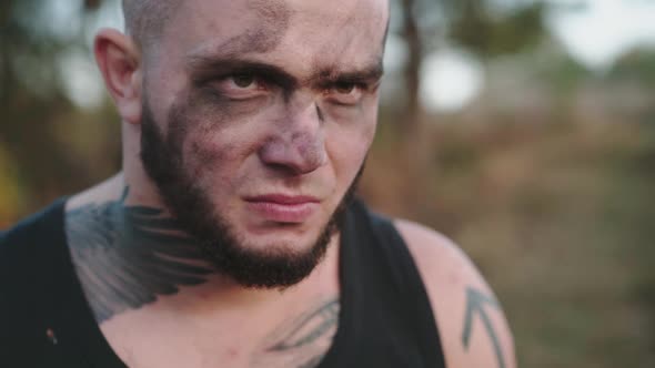 Aggressive Brutal Man with Soot During Sharpening Shavings with Knife on Nature alt