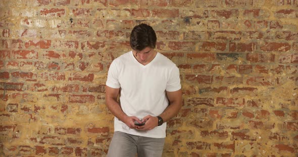 Caucasian man using a smartphone on a brick wall alt