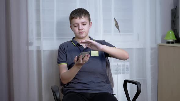Successful Teenager Scatters a Lot of 100Dollar Bills While Sitting in a Chair alt
