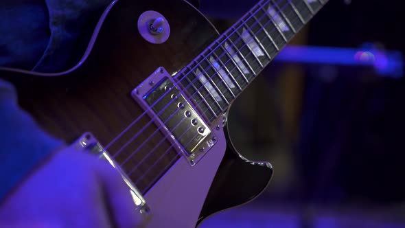 Close-up of male guitarist hands playing electric guitar on big concert hall stage alt