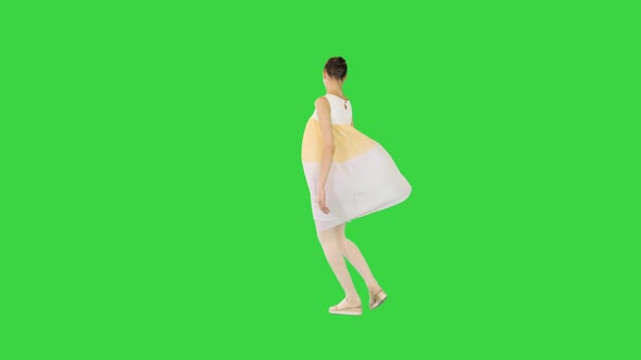 Young Beautiful Girl in Whiteyellow Dress Walks Dancing and Smiling on a Green Screen Chroma Key