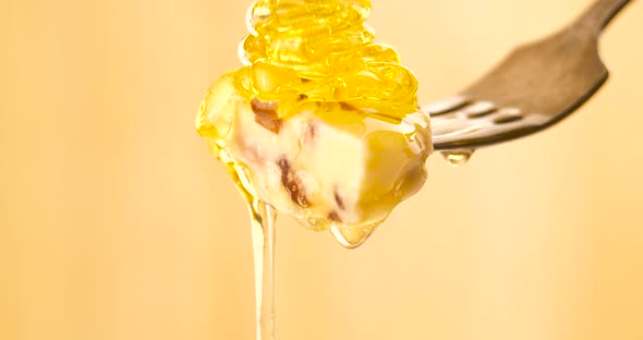 Liquid Organic Honey Dripping on a Fork with Cheese on a Light Background alt