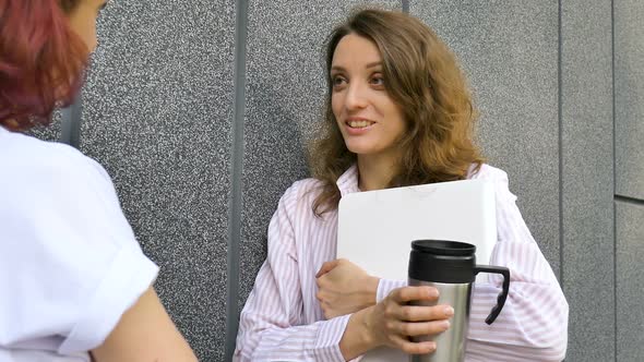 Two Successful Businesswomen are Talking About a the Project While Standing Near the Wall Outside alt