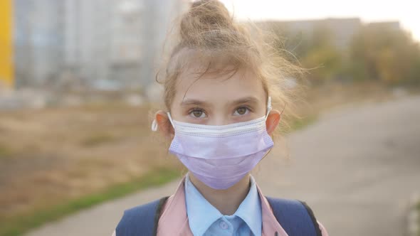 Portrait of a Girl in a Protective Medical Mask Looking at the Lens