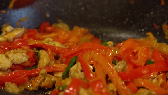 Frying pan fry fillet chicken pieces, red bell peppers and green onions with soy sauce. Frying alt