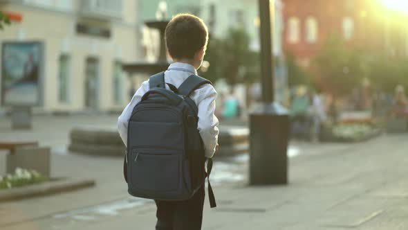 A First Grader with a Backpack on His Back Goes Home From School After the End of the Lessons