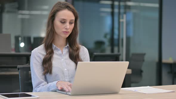 Young Businesswoman Thinking while using Laptop at Work alt