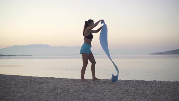 A Beautiful Girl Spreads a Karemat By the Sea and Begins To Train. Sports, Yoga, Beach.