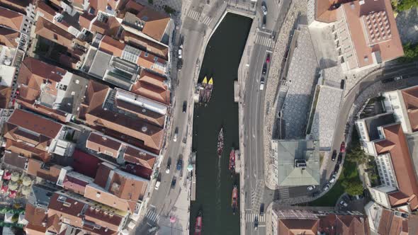 Moliceiros with tourists on busy Ria de Aveiro urban canals. Top down aerial cityscape alt