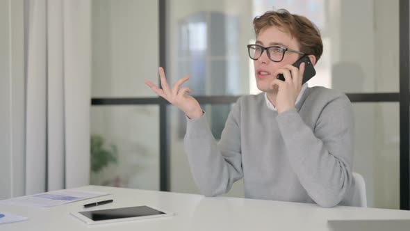 Young Man Talking on Phone in Modern Office alt