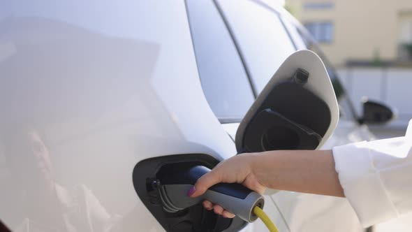 Woman Hand Holding Electric Car Cable for Recharge Plug In Hybrid Electric Vehicle alt