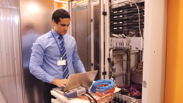 Technician talking on mobile phone in server room alt