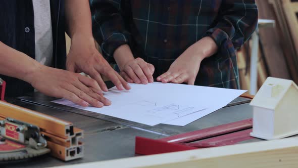 Close up of Man and Woman discussion construction for built-in furniture project in workshop alt
