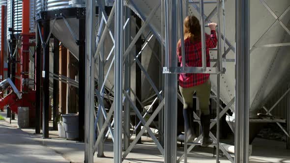 Rear view of caucasian female worker climbing ladder by storage tank 4k alt