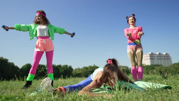 Slim Brunette Flexible Sportswoman Stretching Muscles As Friends in Retro Clothes Exercising at alt