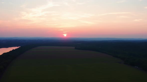 Beautiful pink orange sun peeks through the clouds and reflects of amazing Potomac River in Maryland alt