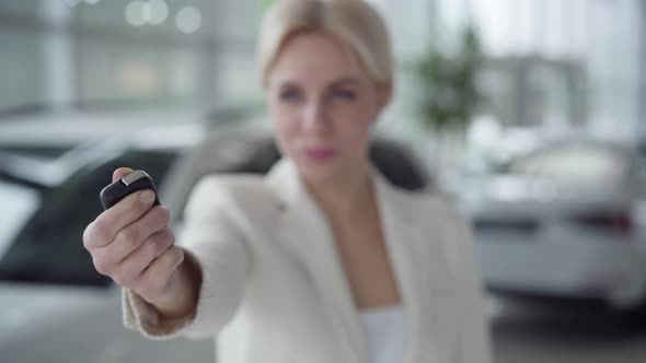 Close-up of Female Caucasian Hand Opening Car Keys. Blurred Blond Woman Smiling at Camera at the alt