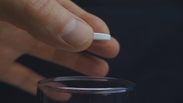 The Hand Releases The Effervescent Tablet Into A Glass Of Water In Slow Motion