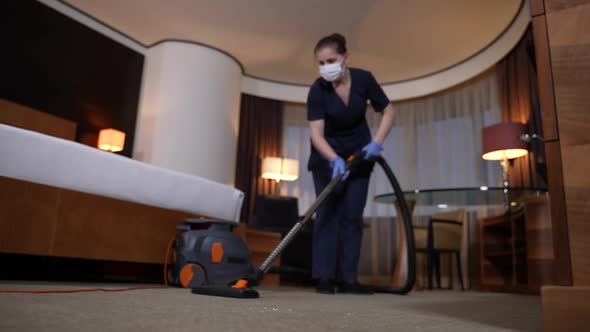 Diligent Housemaid Vacuuming Carpet in Hotel Room alt