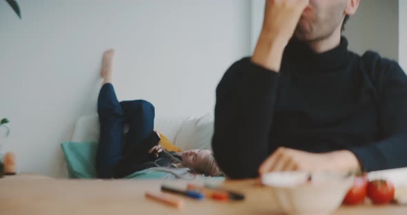 Young man eating apple while sitting at a table alt