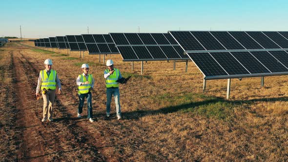 Three Solar Energy Specialists Walking at a Solar Power Facility alt