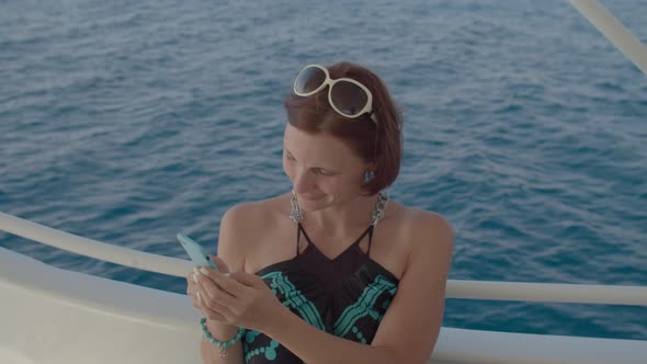 Woman Using Smart Phone Sailing on Boat alt