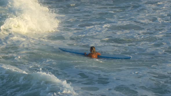 A young woman surfing in a bikini on a longboard surfboard. alt