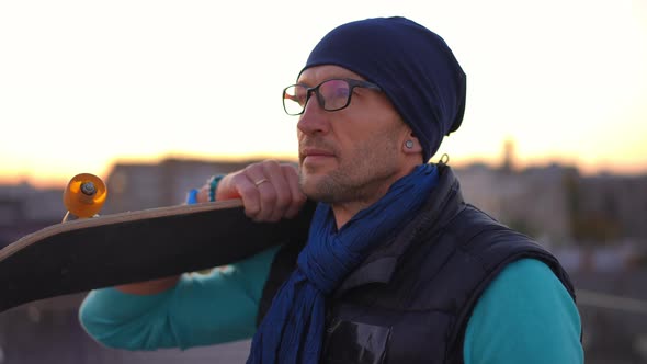 Side View Relaxed Man with Skateboard on Shoulder Turning Looking at Camera with Confident Facial alt