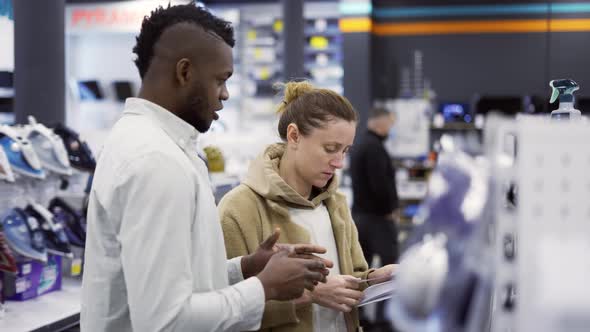 Shop Assistant Giving Advice to Woman in Store alt